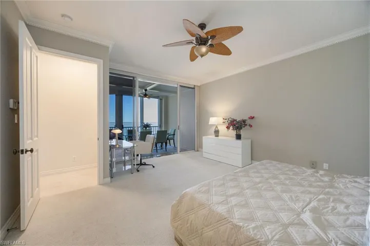 Carpeted bedroom featuring crown molding, expansive windows, and a ceiling fan