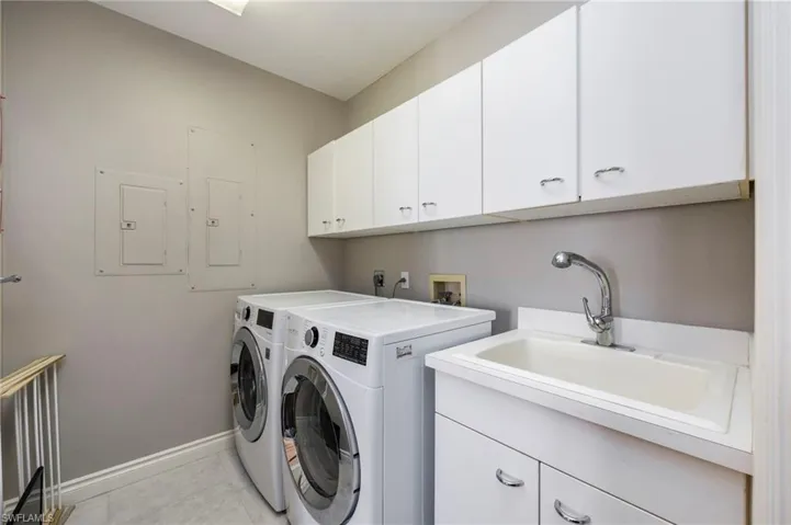 Laundry room featuring electric panel, cabinet space, and separate washer and dryer