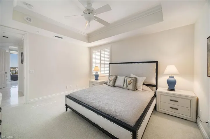 Bedroom with crown molding, a raised ceiling, ceiling fan, and light carpet