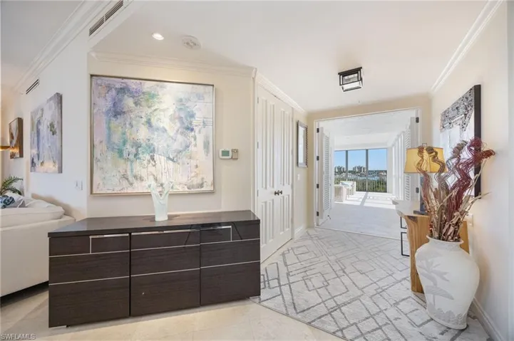 Hallway with crown molding and light tile patterned floors