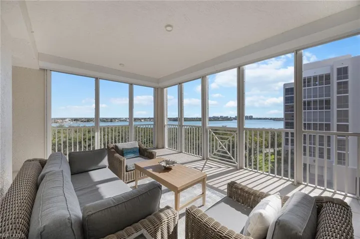 Sunroom featuring a wall of windows, healthy amount of natural light, a water view, and a textured ceiling