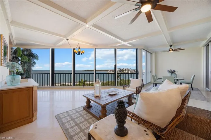 Sunroom with a textured ceiling, coffered ceiling, a wall of windows, beamed ceiling, and a water view