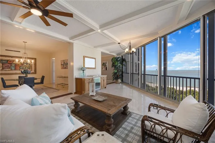 Living room with a chandelier, a water view, a textured ceiling, a wall of windows, and a ceiling fan