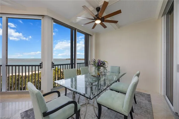 Dining room with a water view, ornamental molding, and ceiling fan
