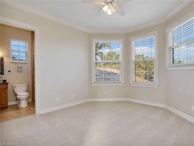 Empty room with ceiling fan, light colored carpet, and crown molding