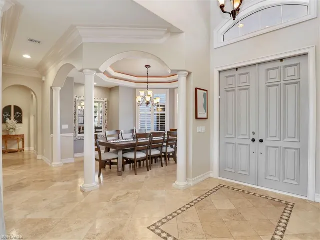 Entrance foyer with decorative columns, ornamental molding, and a chandelier
