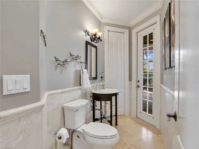 Bathroom featuring tile patterned floors, tile walls, toilet, and ornamental molding