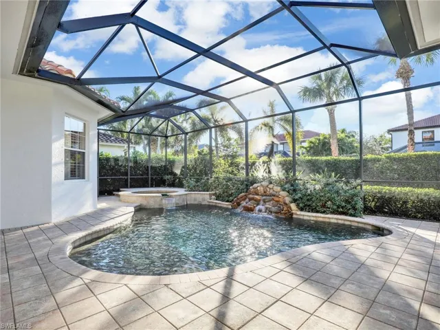 View of pool featuring pool water feature, a patio, glass enclosure, and an in ground hot tub