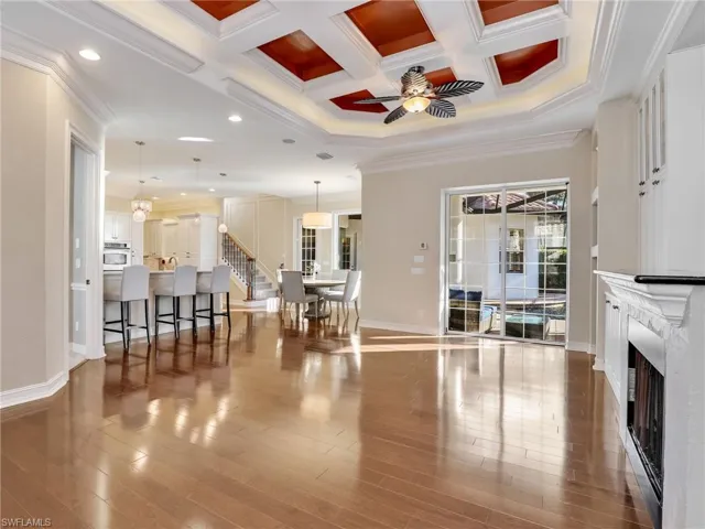 Living room featuring ceiling fan with notable chandelier, crown molding, and coffered ceiling