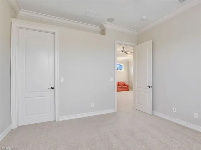 Spare room featuring light carpet, ceiling fan, and crown molding