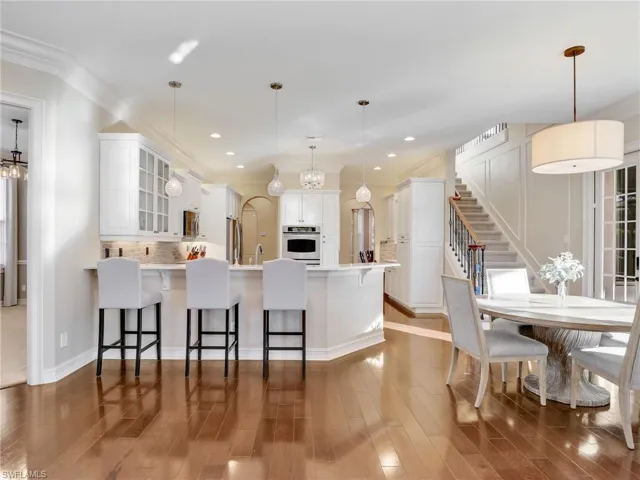 Kitchen with white cabinets, appliances with stainless steel finishes, a breakfast bar area, and pendant lighting