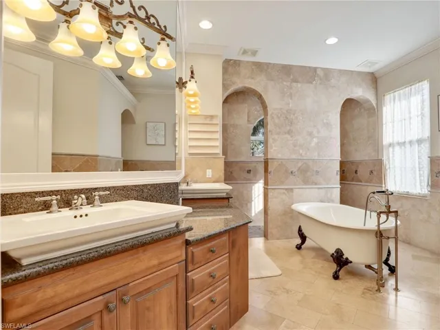 Bathroom featuring a tub to relax in, vanity, tile walls, and ornamental molding
