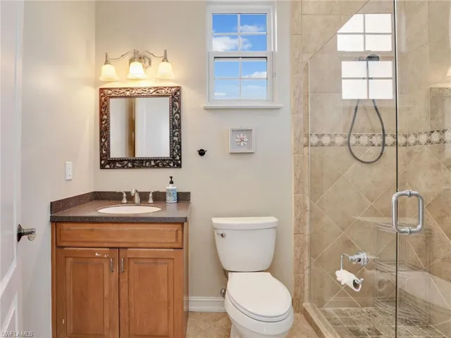 Bathroom featuring a shower with shower door, toilet, vanity, and tile patterned flooring