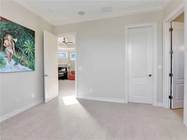 Spare room featuring ceiling fan, light colored carpet, and crown molding