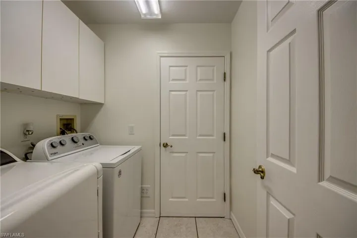 Washroom featuring cabinets, independent washer and dryer, and light tile patterned floors