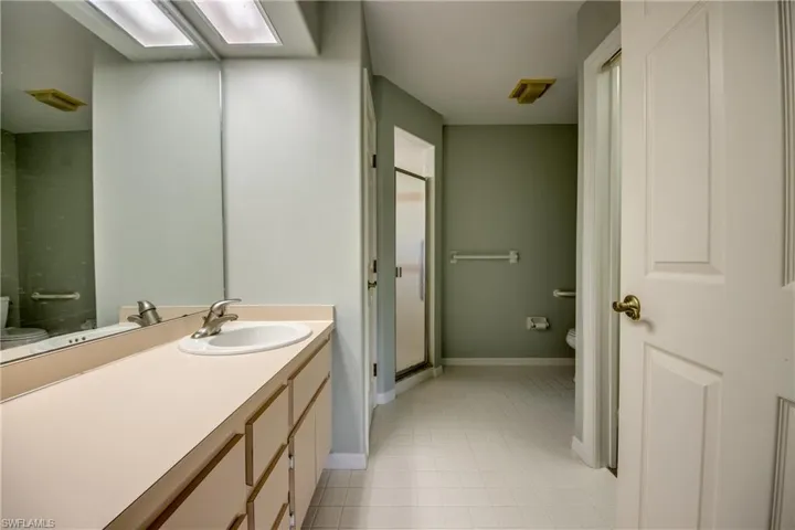 Bathroom with a shower with door, vanity, tile patterned flooring, and toilet