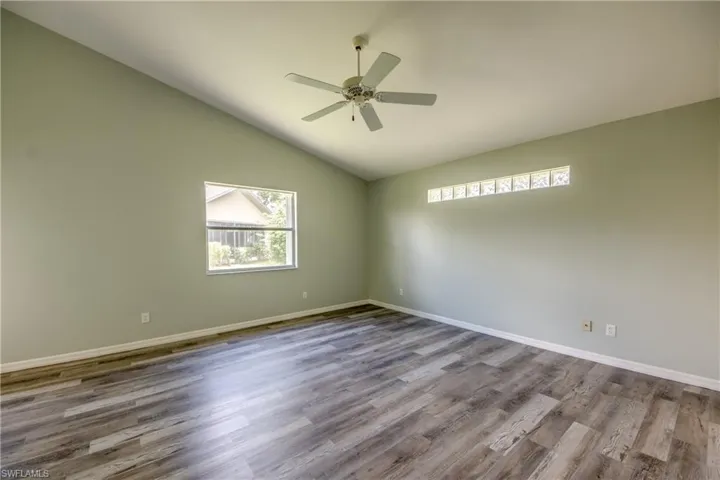 Spare room with vaulted ceiling, ceiling fan, and hardwood / wood-style floors