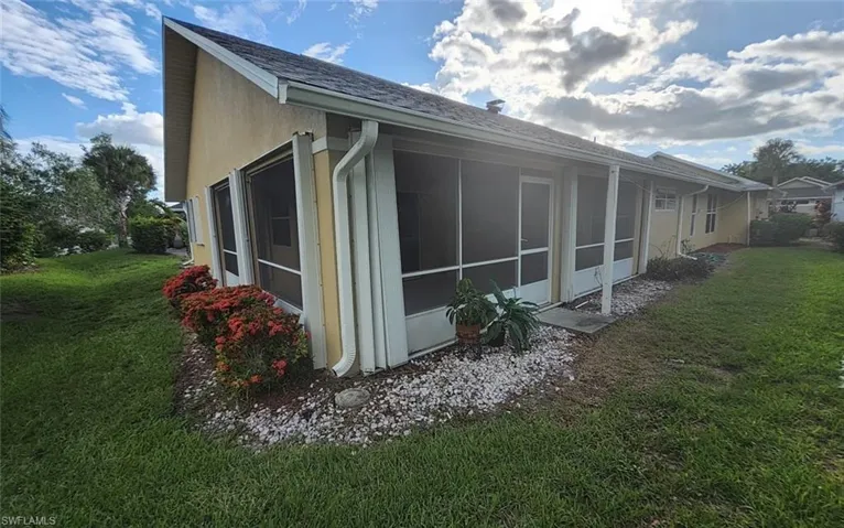 View of side of home featuring a sunroom and a lawn