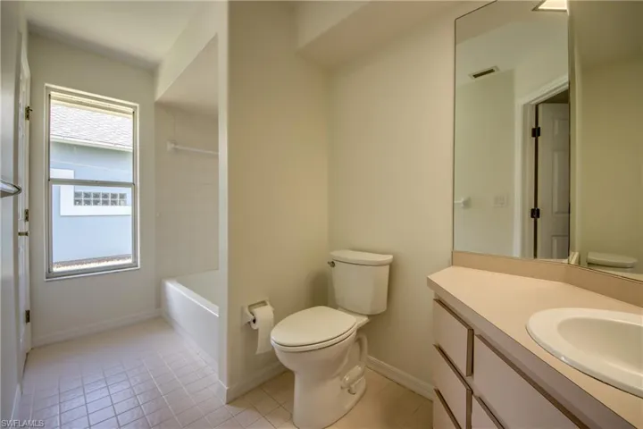 Full bathroom with vanity, tiled shower / bath, toilet, and tile patterned floors