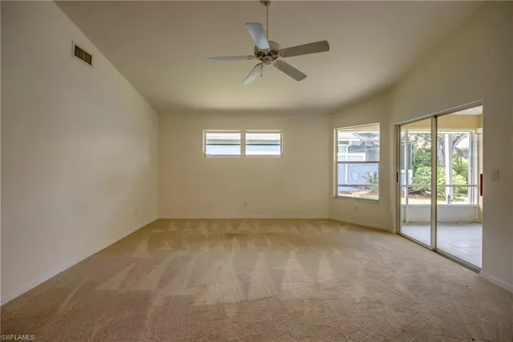 Carpeted empty room with plenty of natural light, ceiling fan, and vaulted ceiling