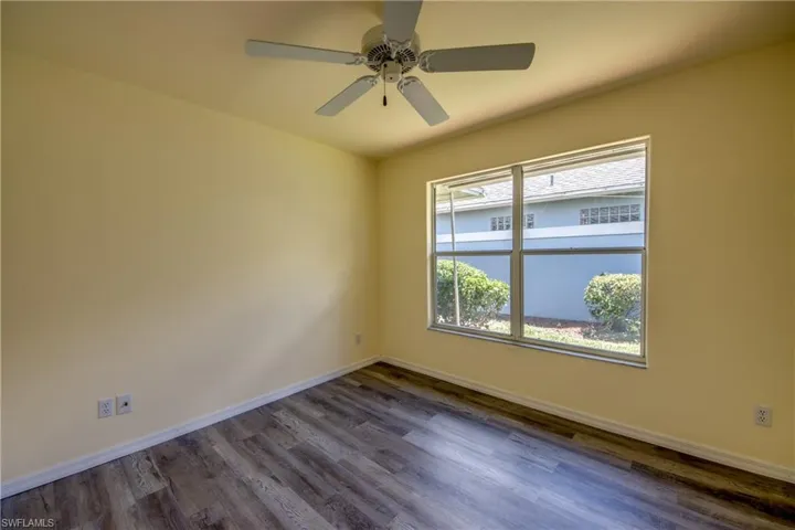 Empty room featuring dark wood-type flooring and ceiling fan