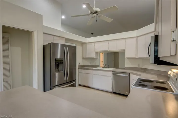 Kitchen with sink, appliances with stainless steel finishes, ceiling fan, and white cabinetry