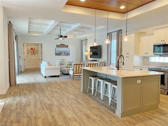 Kitchen with appliances with stainless steel finishes, light wood-type flooring, a center island with sink, and sink