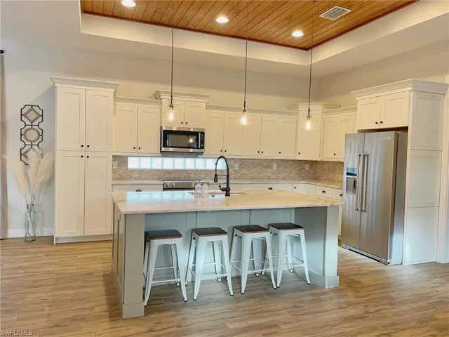 Kitchen featuring white cabinetry, wooden ceiling, light wood-type flooring, and appliances with stainless steel finishes
