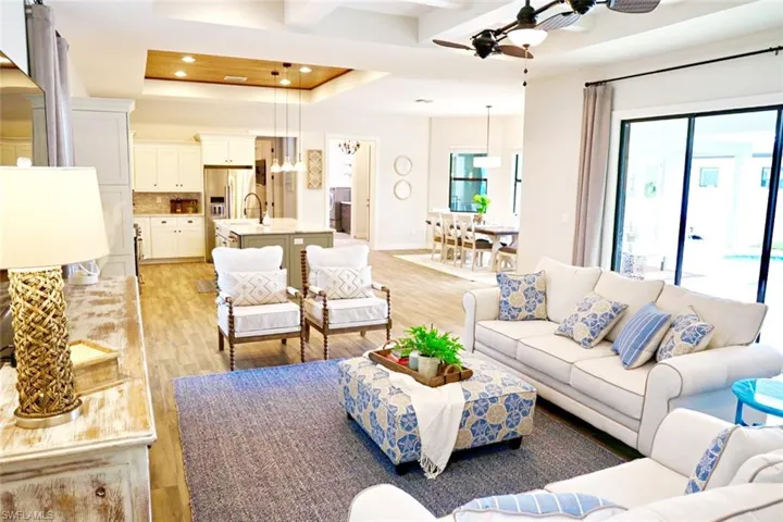 Living room with a raised ceiling, light hardwood / wood-style flooring, plenty of natural light, and ceiling fan