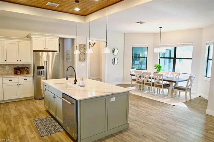 Kitchen with wooden ceiling, appliances with stainless steel finishes, hanging light fixtures, and light wood-type flooring