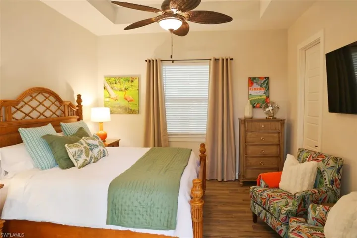 Cabana bedroom with ceiling fan and dark wood-type flooring