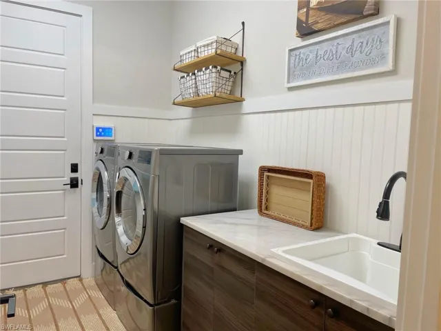 Clothes washing area featuring separate washer and dryer and sink