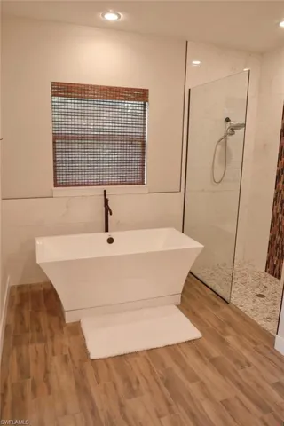 Bathroom featuring hardwood / wood-style floors and shower with separate bathtub