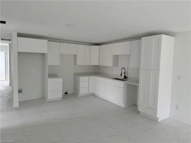 Kitchen featuring sink, light tile patterned floors, and white cabinets