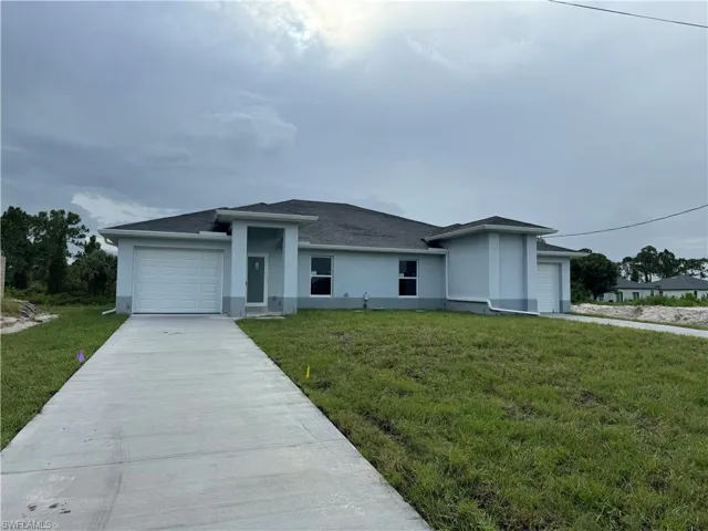 View of front facade featuring a garage and a front lawn
