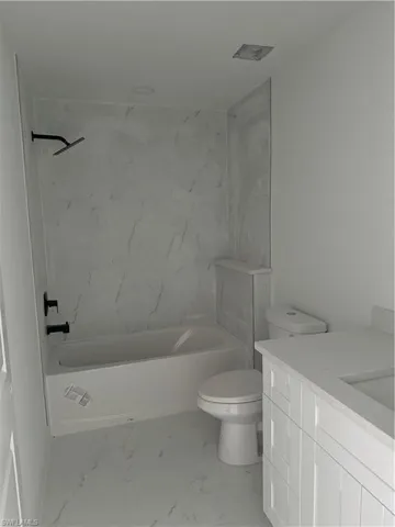 Full bathroom with tile patterned flooring, tiled shower / bath combo, toilet, and vanity