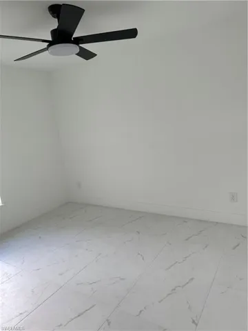 Empty room featuring light tile patterned floors and ceiling fan