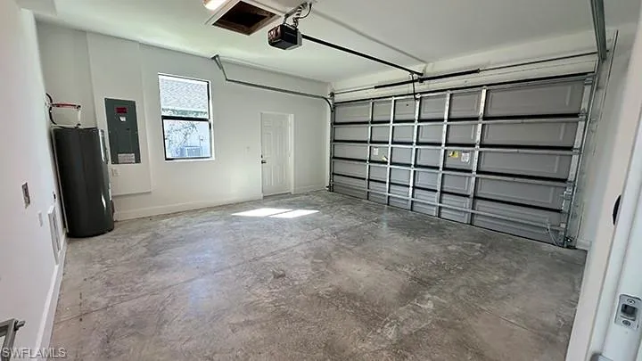 Garage featuring water heater, electric panel, and a garage door opener