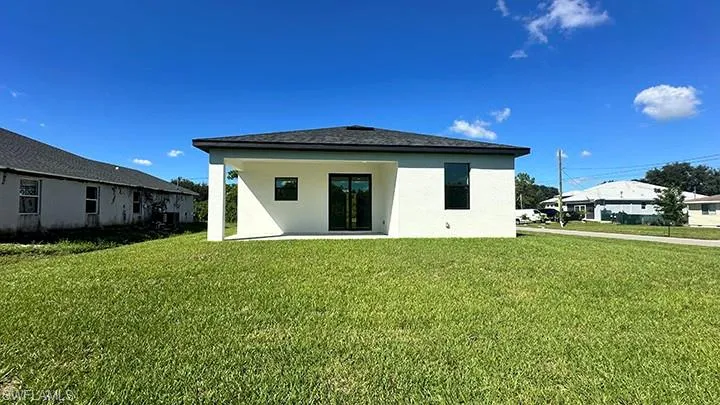 Back of house featuring a lawn, stucco siding, and a patio