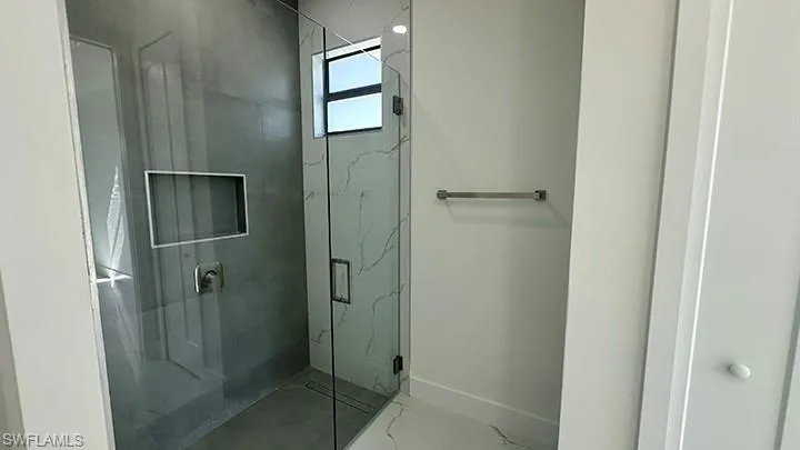 Bathroom featuring a marble finish shower and baseboards