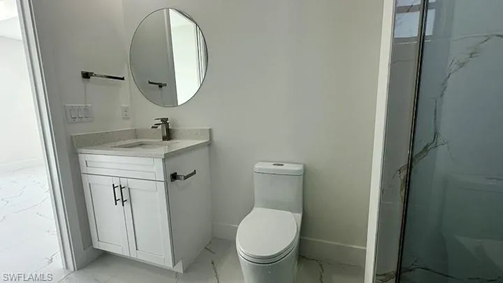 Bathroom with light marble finish flooring, vanity, and a marble finish shower
