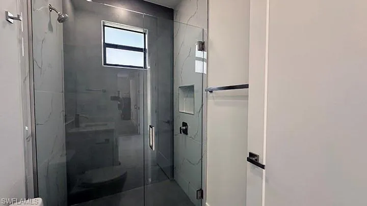 Bathroom with a marble finish shower and toilet