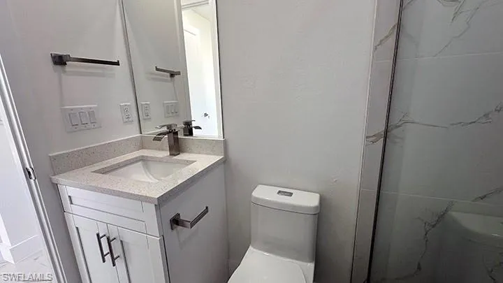 Full bathroom with vanity, a marble finish shower, and marble look tiles