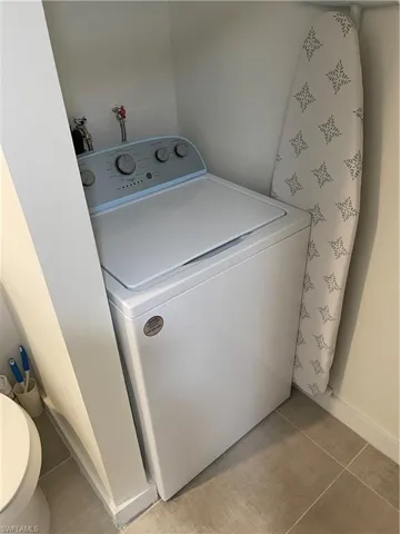Washroom with tile patterned flooring and washer / dryer