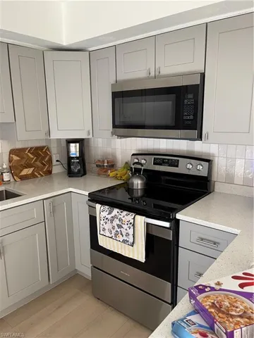 Kitchen featuring gray cabinets, decorative backsplash, electric range, and light hardwood / wood-style floors
