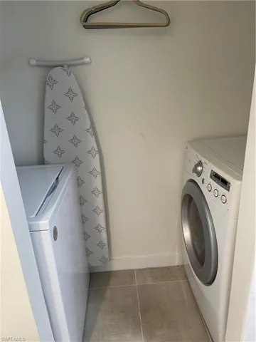 Laundry room with dark tile patterned flooring and washing machine and clothes dryer