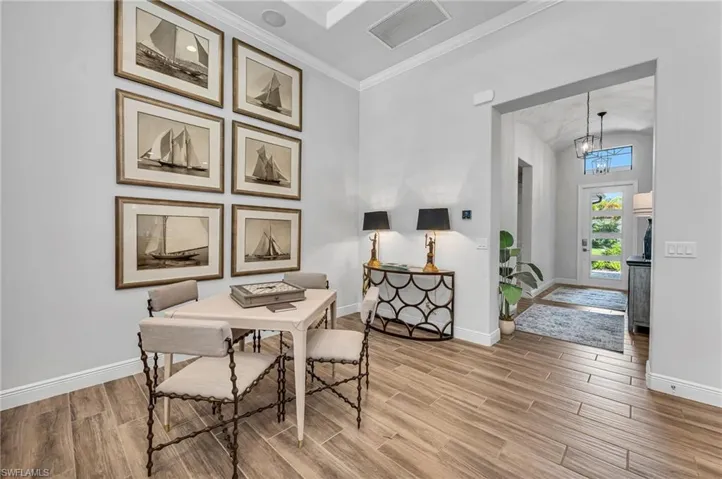 Game table and entry foyer with wood-look porcelain flooring and crown molding