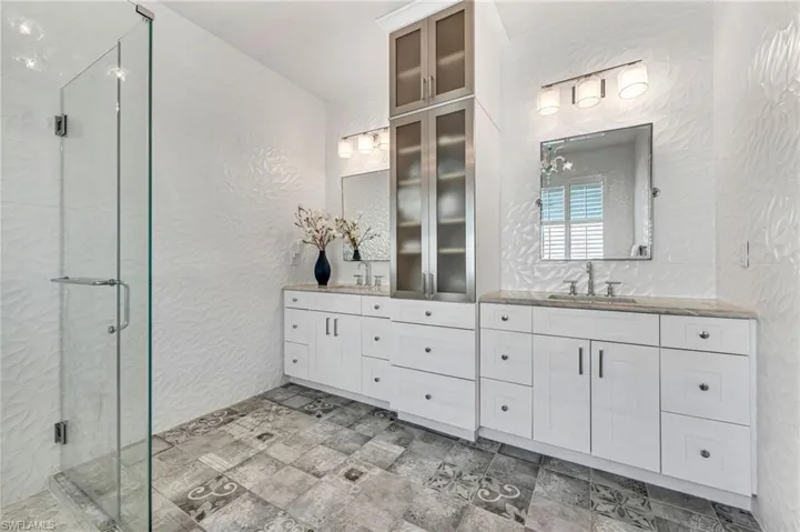 Bathroom with tile floors, dual sink vanity, and a frameless shower