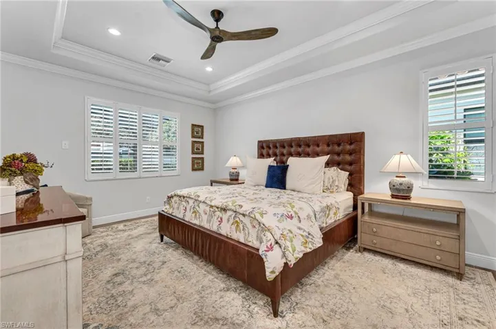 Master Bedroom with ceiling fan, double crown molding, a tray ceiling and room for chairs.