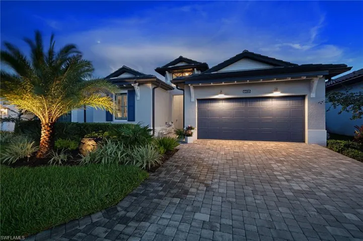 View of front facade with upgraded landscaping and lighting.